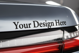 Close-up of the rear trunk area of a silver car with the text 'Your Design Here' printed on the trunk lid.